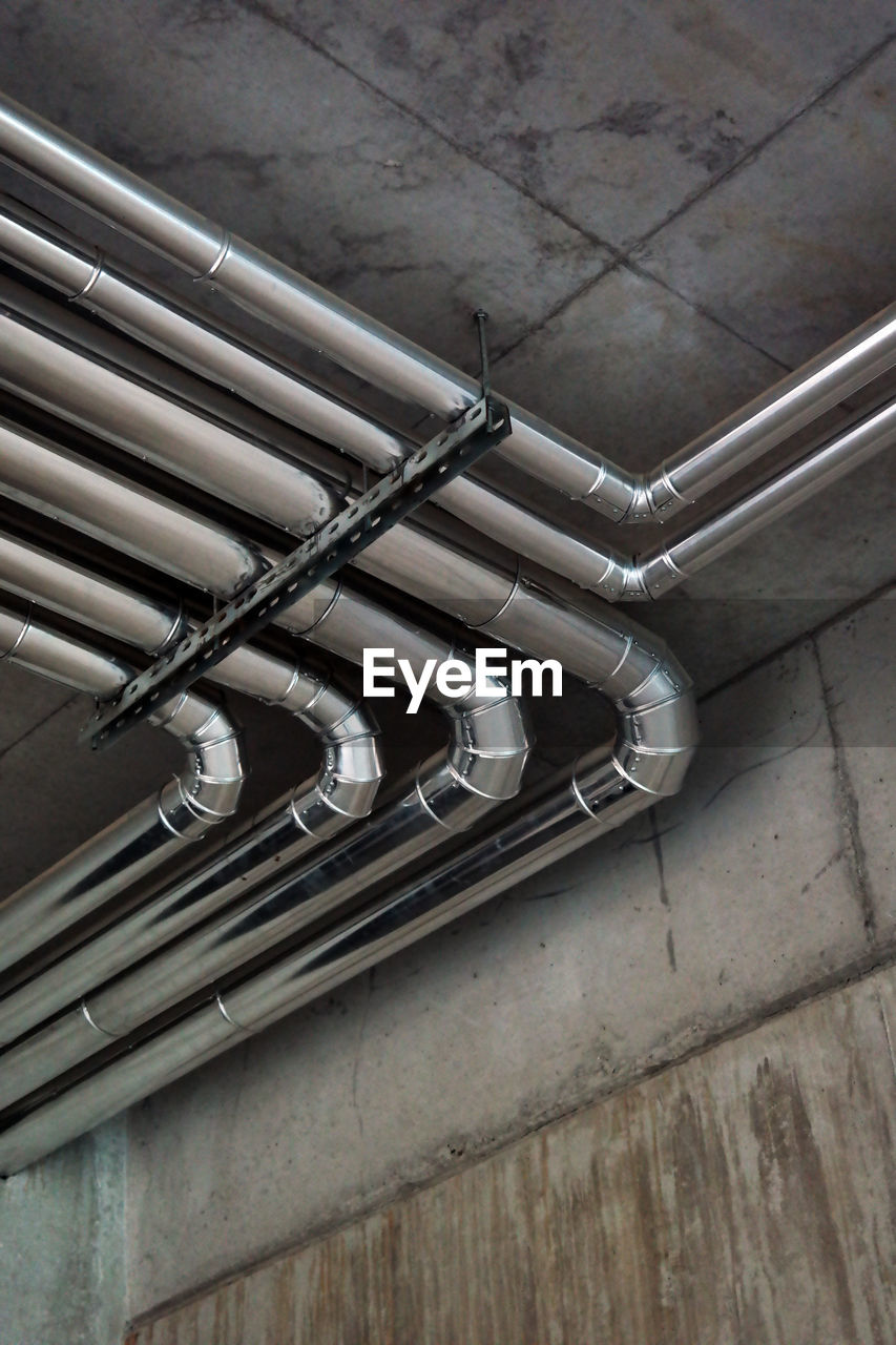 HIGH ANGLE VIEW OF PIPES ON FLOOR AGAINST WALL