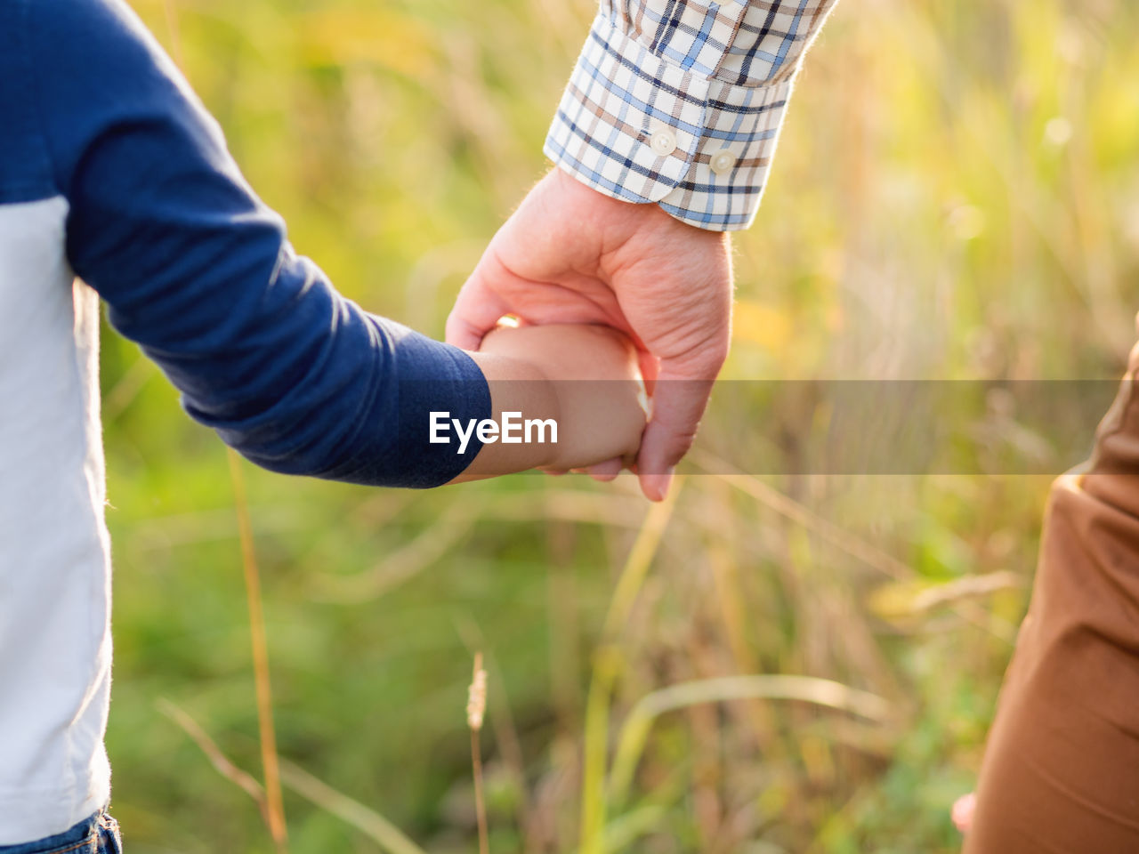 Father and son hold hands. emotional and moral support.man and boy shake hands.golden hour outdoors.