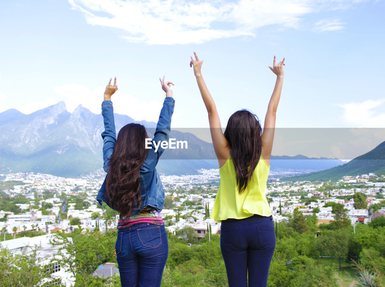 REAR VIEW OF WOMEN STANDING AGAINST MOUNTAIN