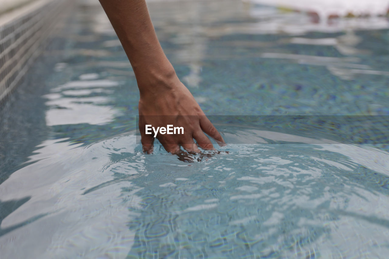 Cropped hand of woman in swimming pool