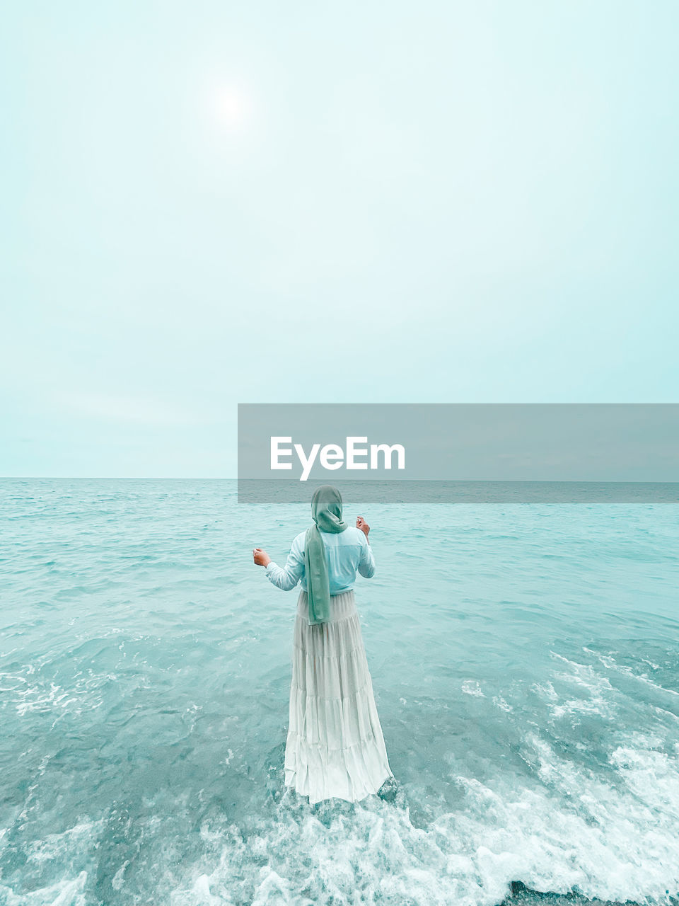 Rear view of woman standing at beach against sky