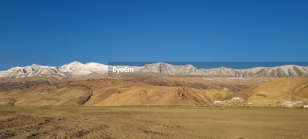 Scenic view of snowcapped mountains against clear blue sky