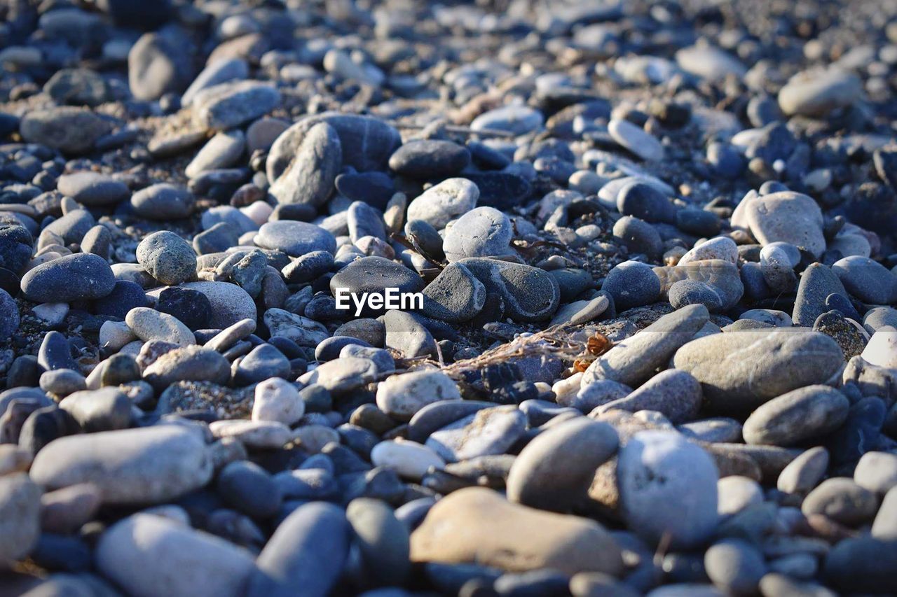 CLOSE-UP OF PEBBLES ON BEACH