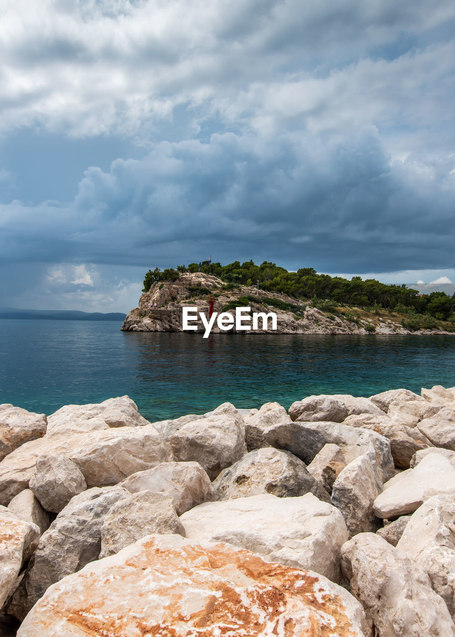 ROCKS BY SEA AGAINST SKY