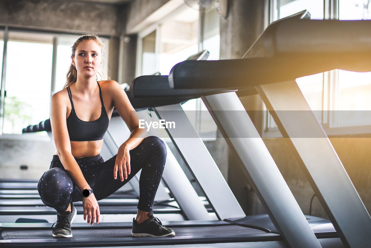 Full length of woman crouching on treadmill