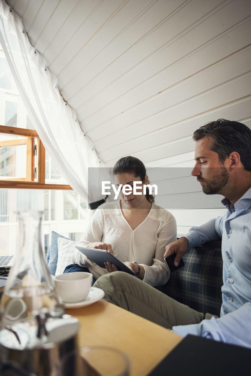 Mid adult businessman with female colleague using digital tablet in office