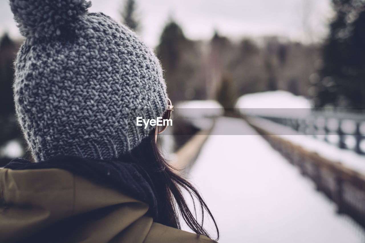 Rear view of woman standing in front of snowcapped footbridge