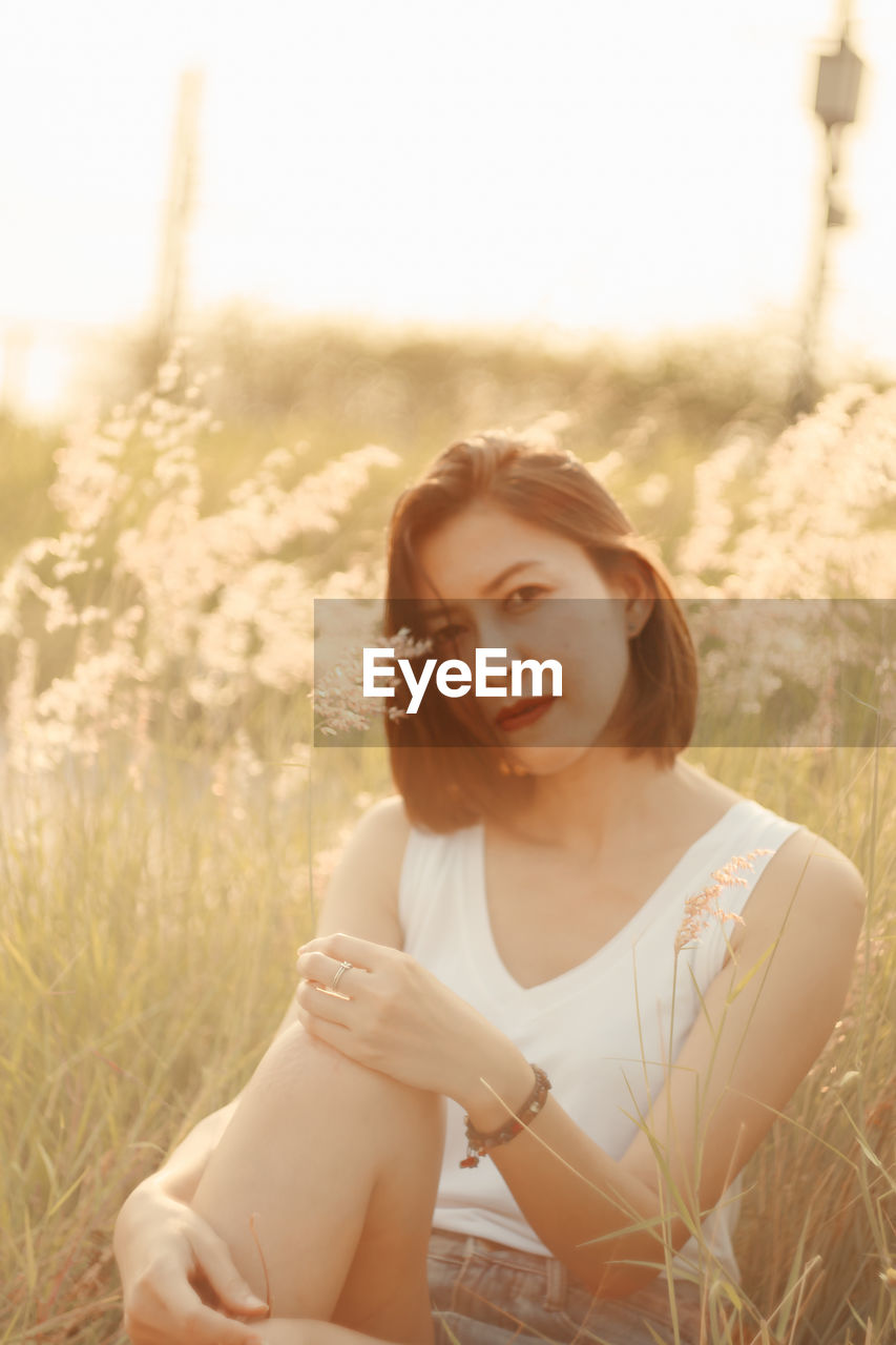 Portrait of woman holding while sitting by plants