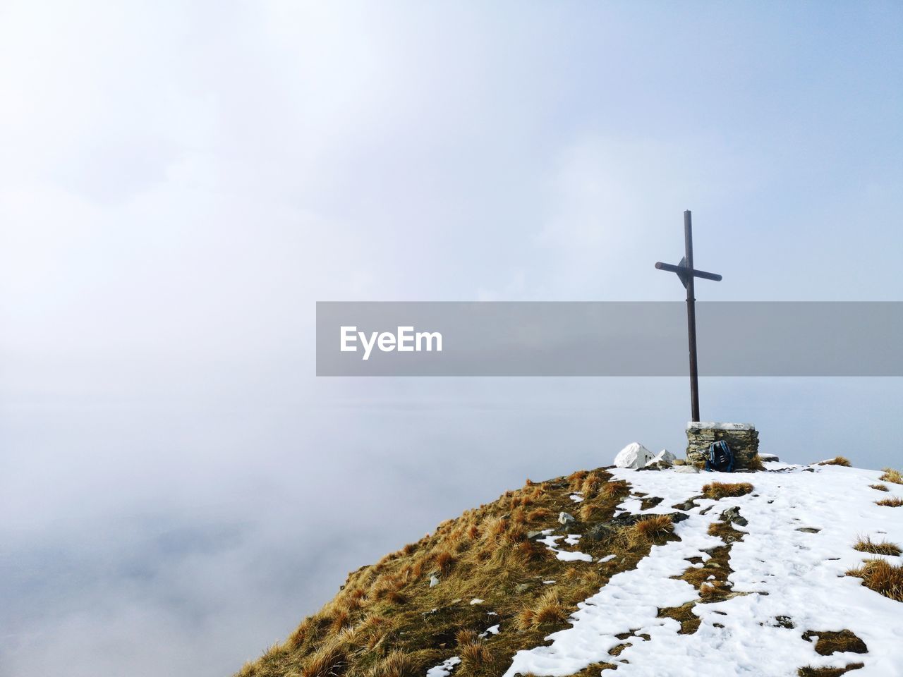 Cross on snowcapped mountain against sky