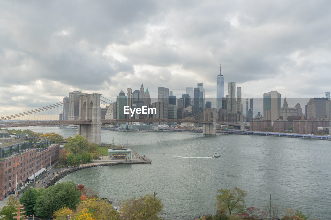 Brookling bridge over river against cloudy sky from manhattan bridge