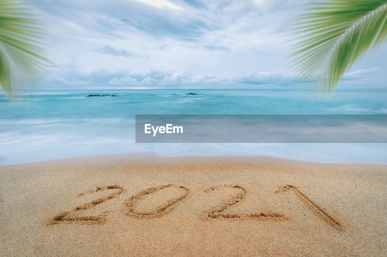 Happy new year 2021, lettering on the beach with wave and blue sea.  new years concept.