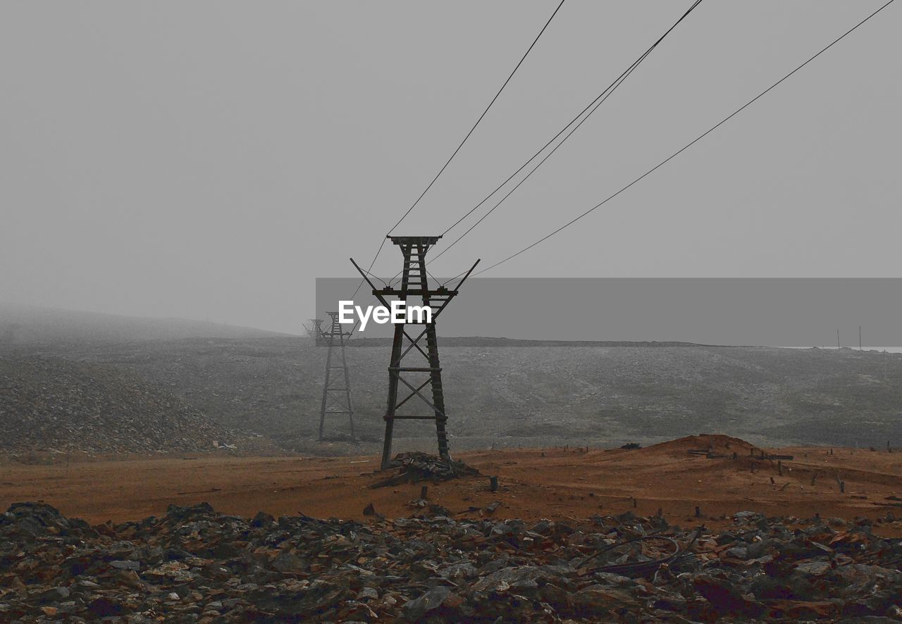 ELECTRICITY PYLONS ON MOUNTAIN AGAINST SKY