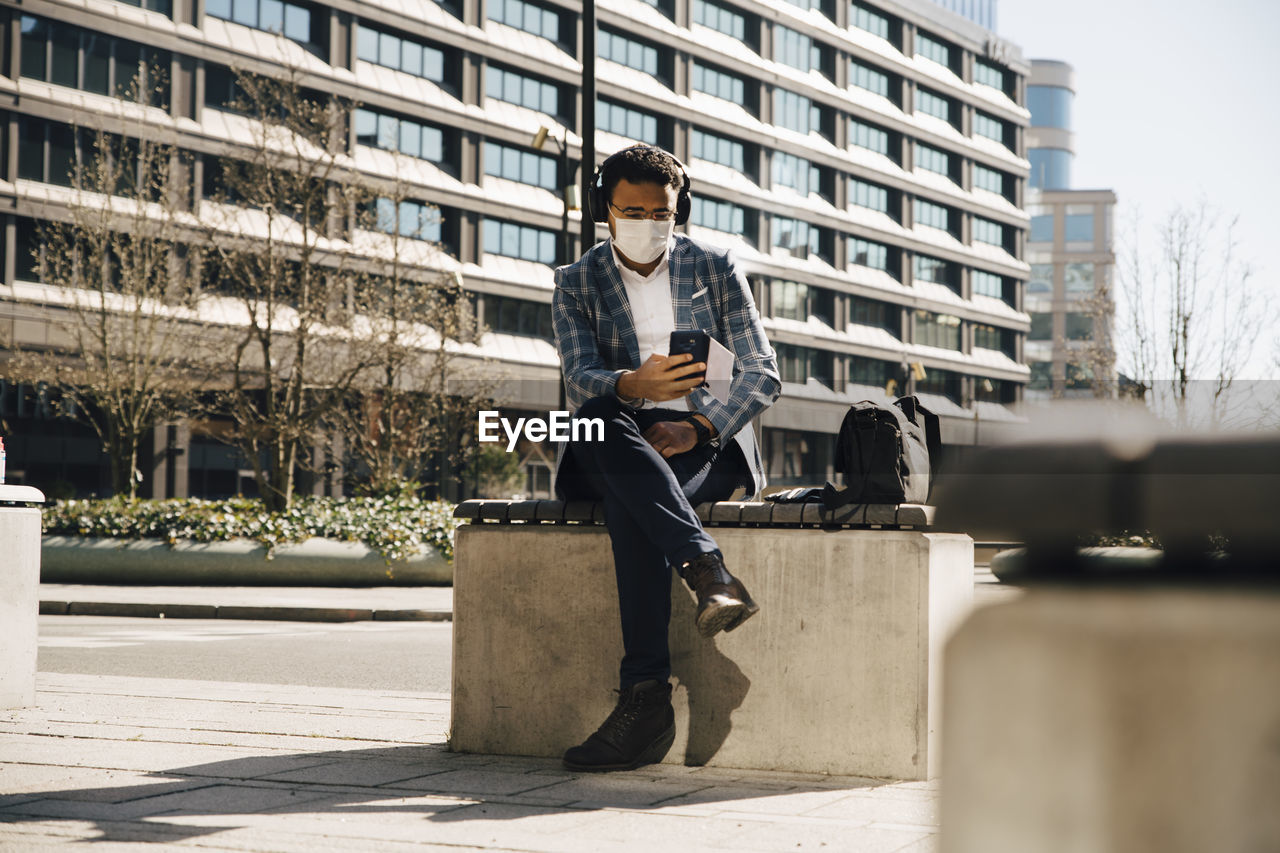 Businessman with face mask using mobile phone