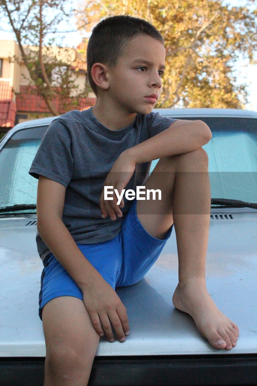 BOY SITTING ON A CAR