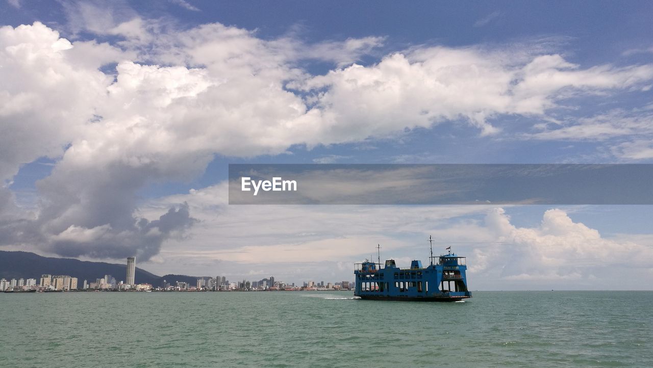 Penang ferry on sea against cloudy sky