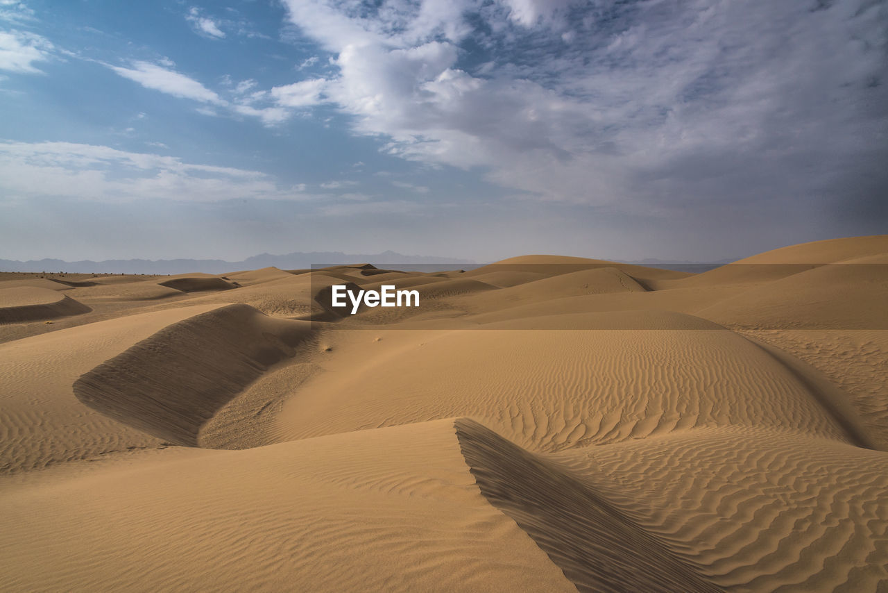 Sand dunes in desert against sky