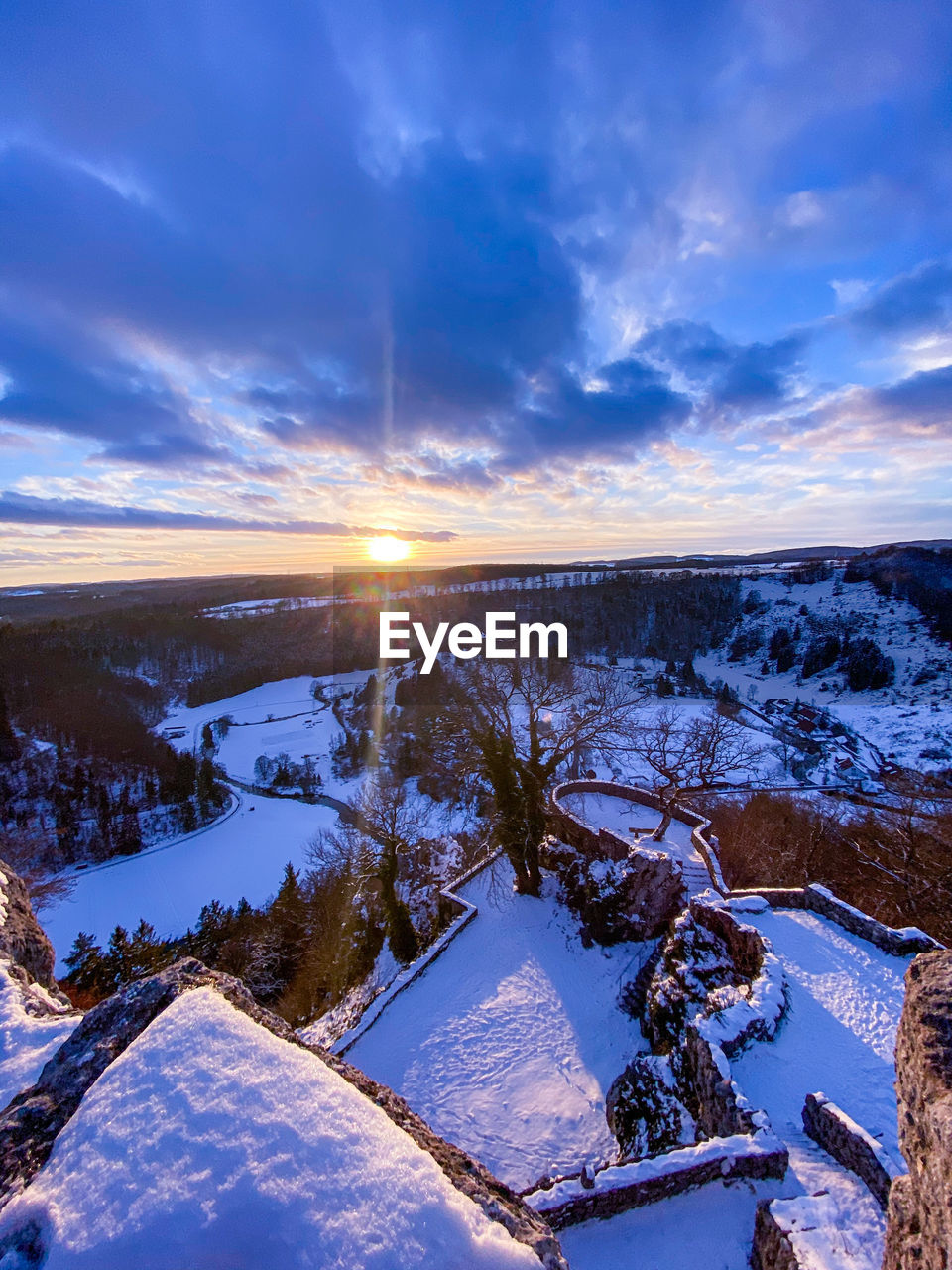 SNOW COVERED LANDSCAPE AGAINST SKY DURING SUNSET