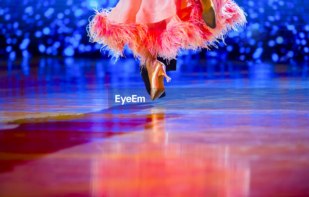 LOW SECTION OF WOMAN DANCING ON FLOOR DURING ORANGE