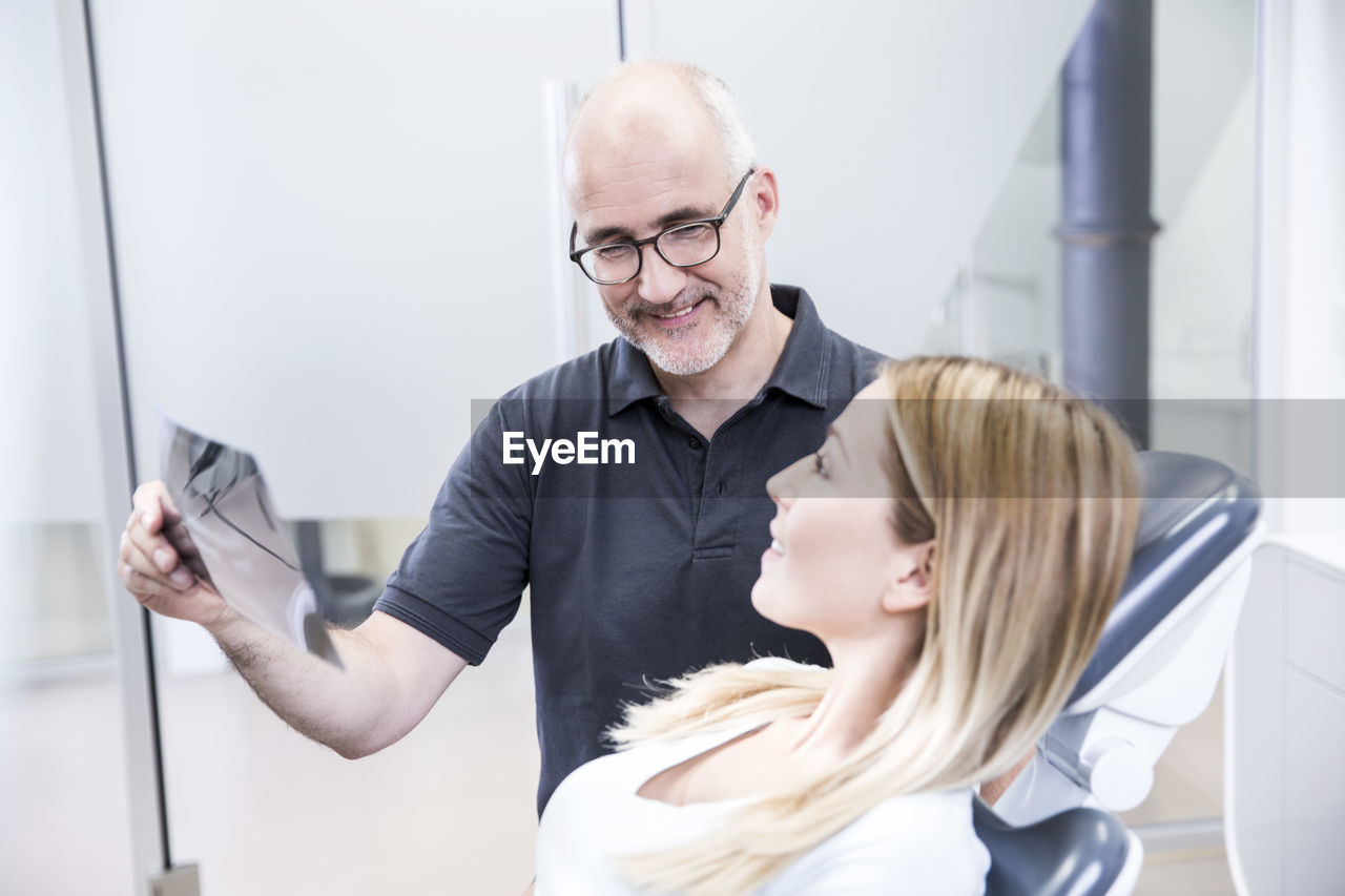 Dentist showing x-ray image to patient, sitting in dentist's chair