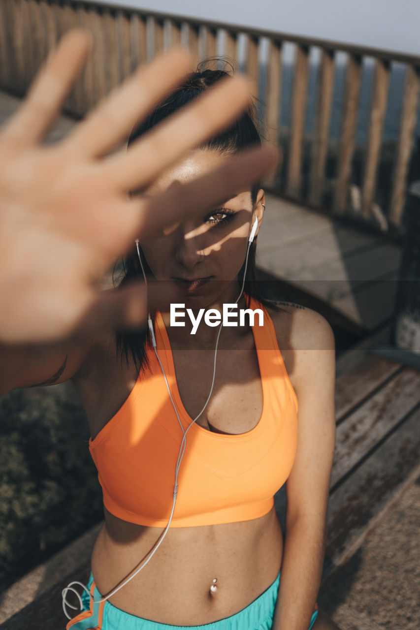 High angle portrait of female athlete shielding while standing outdoors during sunny day