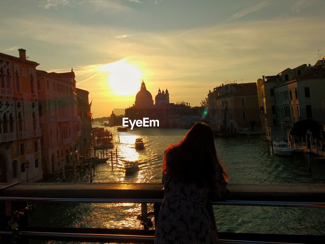 REAR VIEW OF WOMAN STANDING AT WATERFRONT