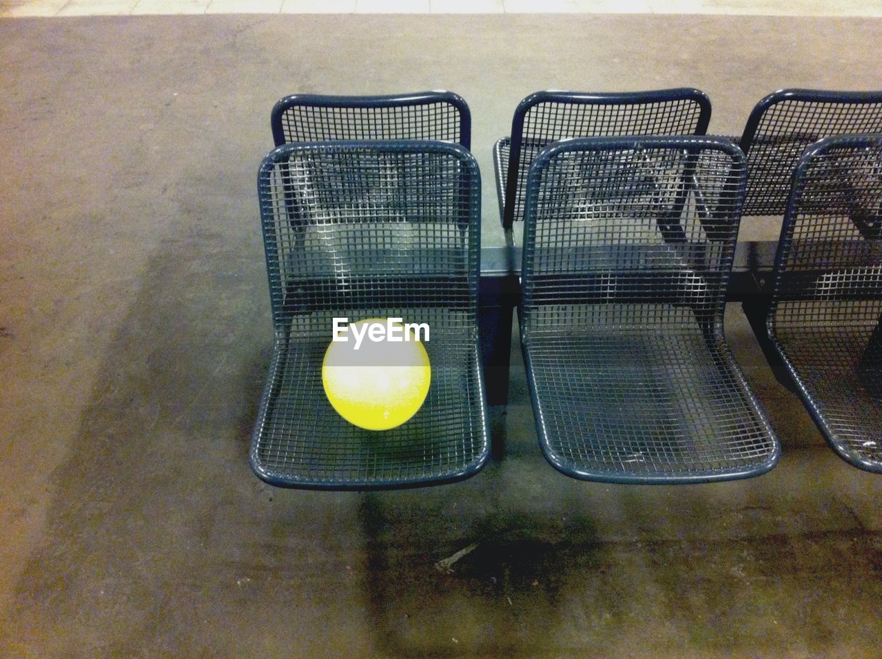 High angle view of yellow ball on metal chairs