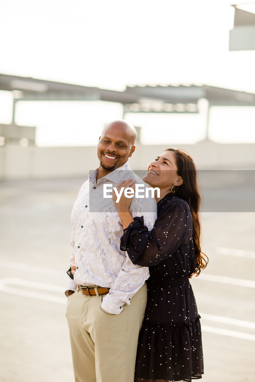 Multiracial late forties couple embracing at sunset in san diego