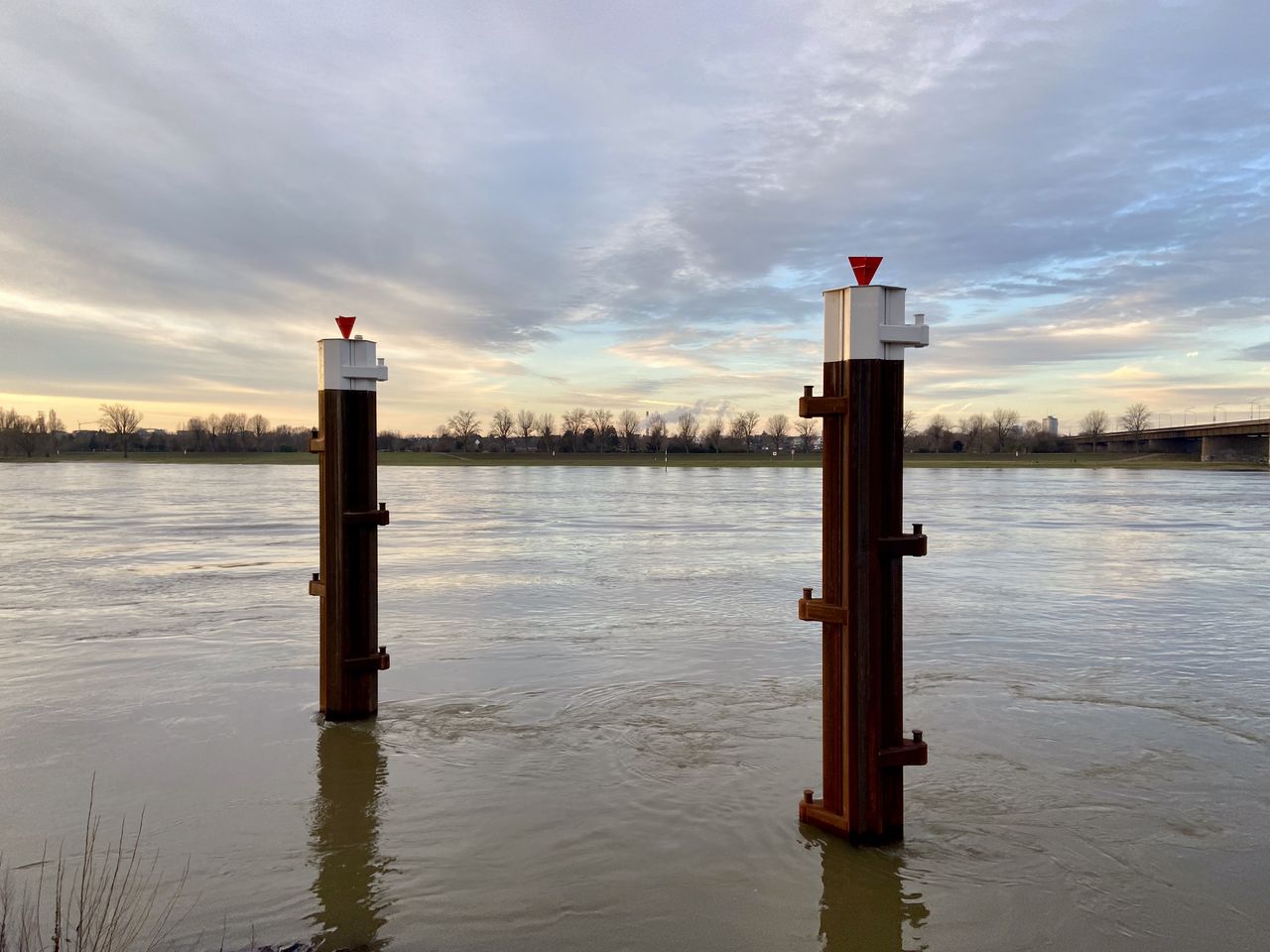 WOODEN POSTS IN LAKE AGAINST SKY