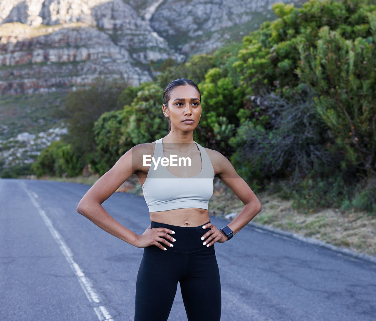 portrait of smiling young woman exercising on road