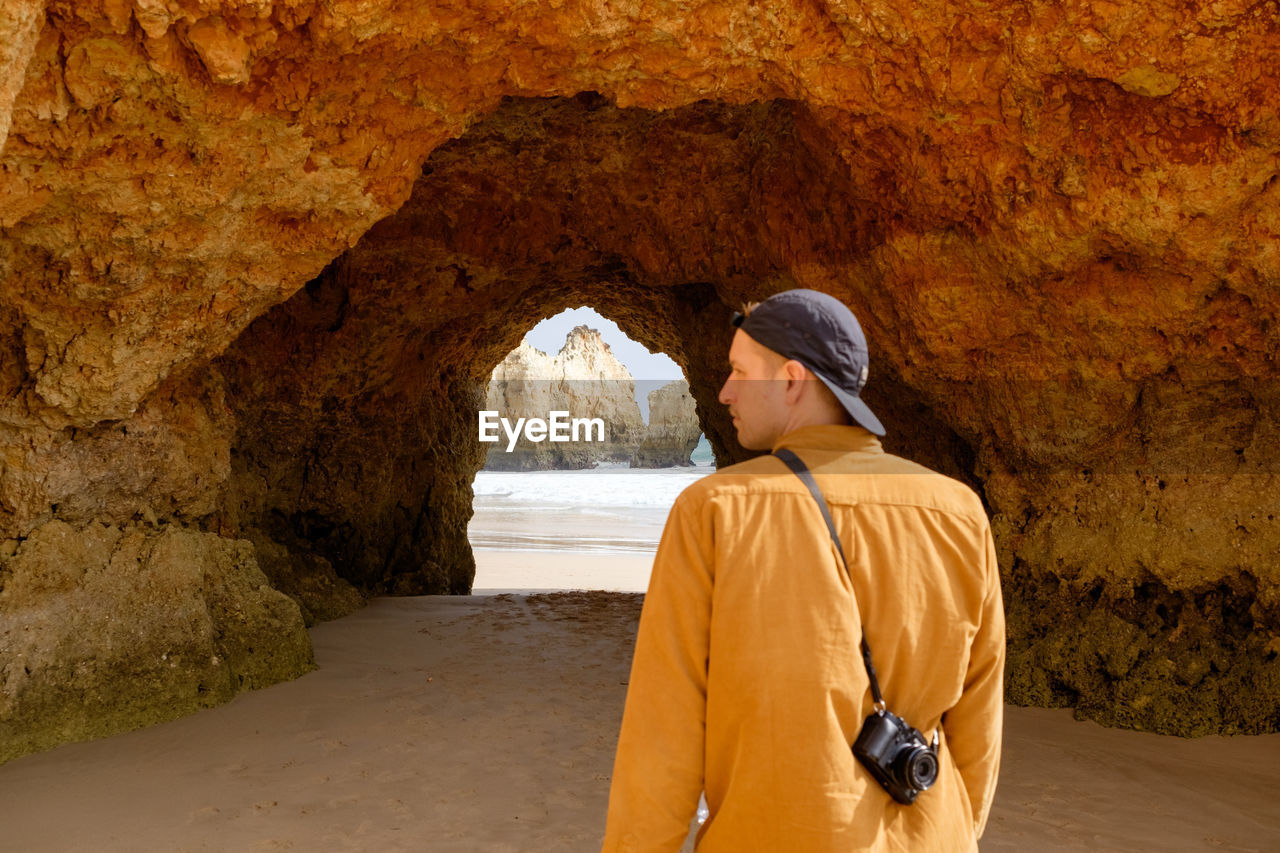 Rear view of man standing against rock formations