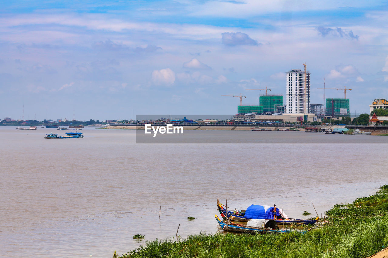 PEOPLE ON BOAT MOORED AT SEA AGAINST SKY