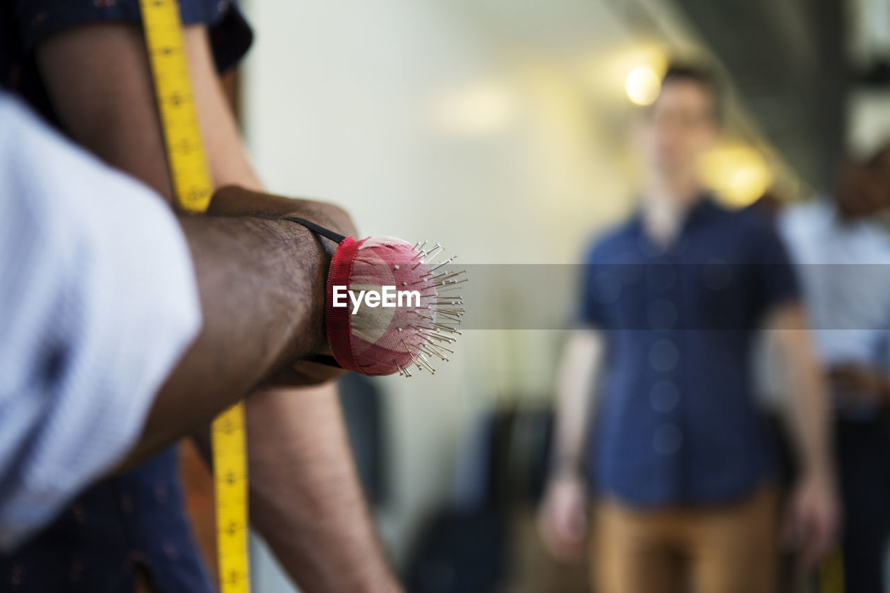 Cropped image of tailor taking measures of customer at workshop