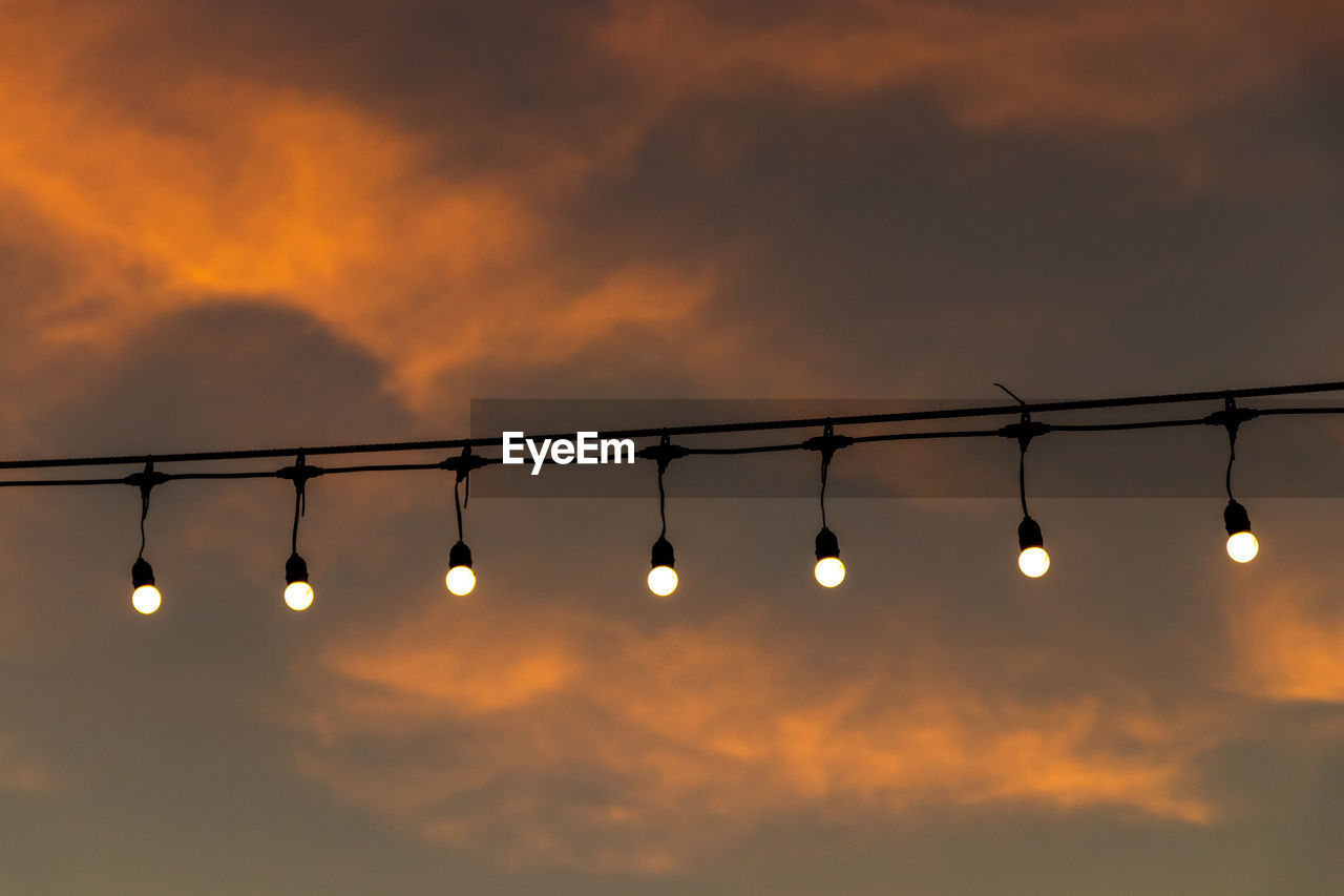 Low angle view of illuminated lights against sky during sunset