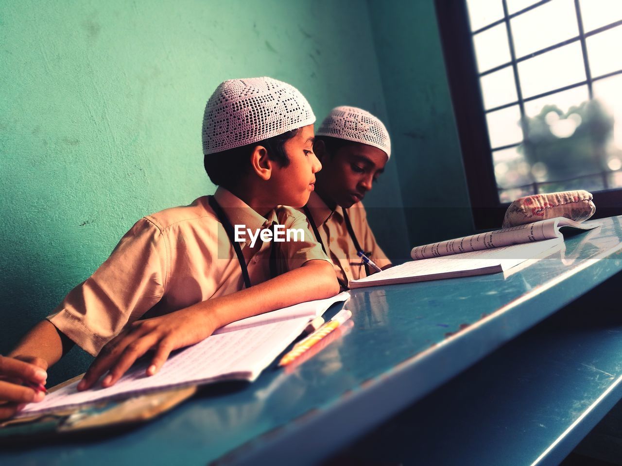 Close-up of students sitting on bench while studying at school