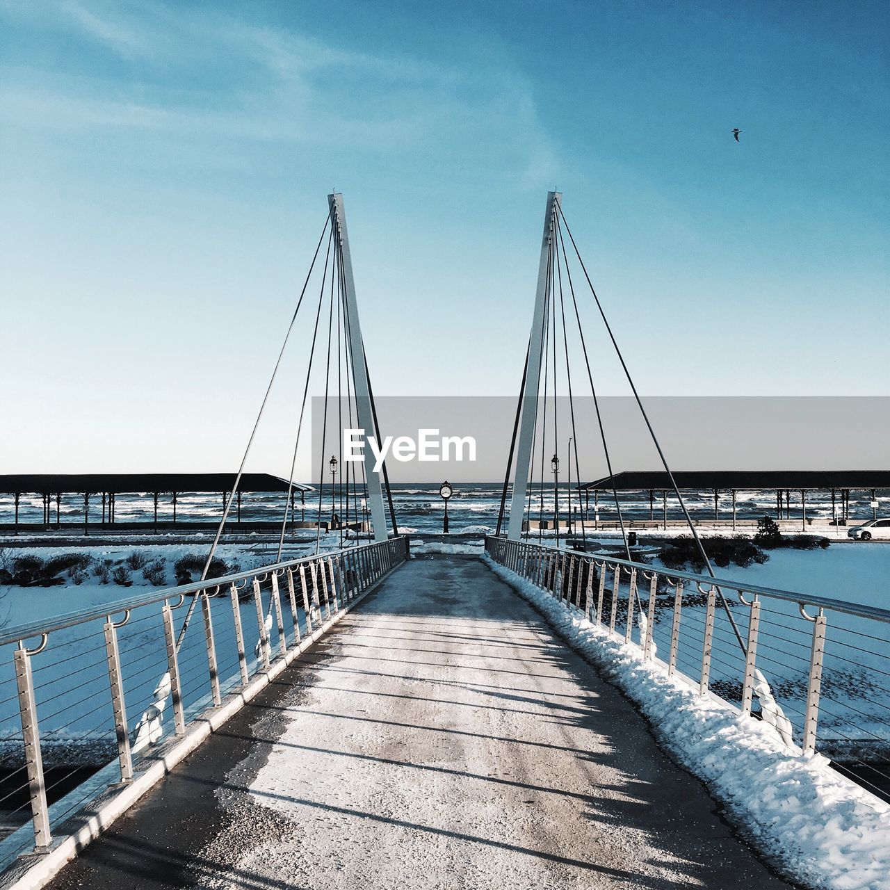 Bridge amidst river against sky during sunny day