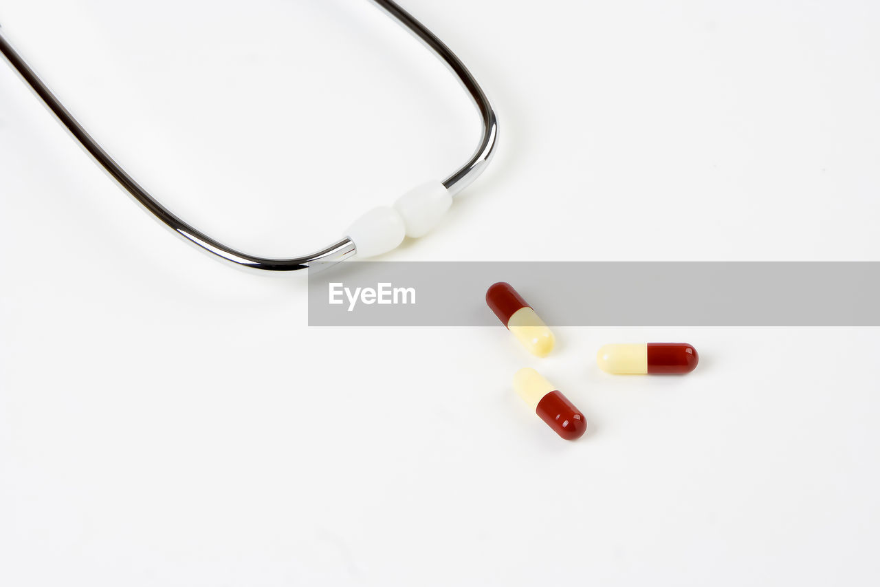 High angle view of stethoscope and capsules against white background