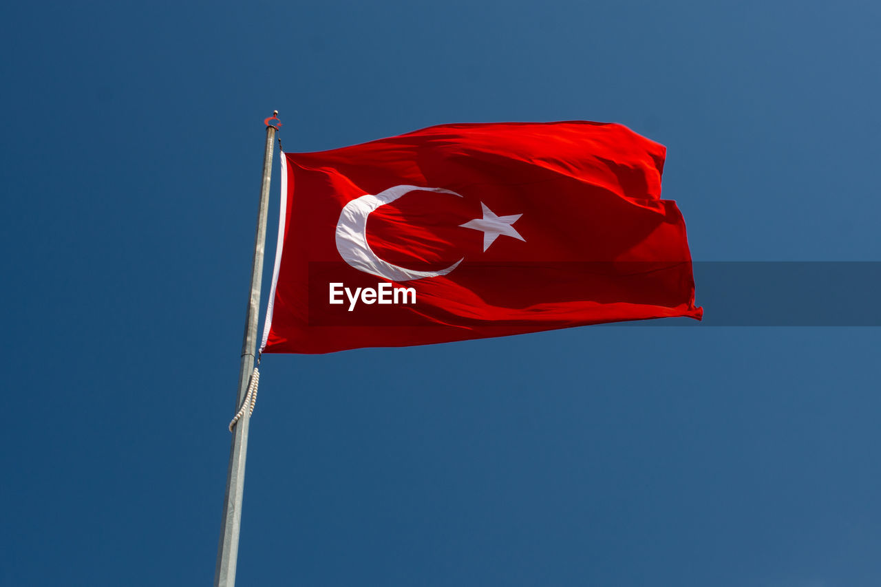 low angle view of american flag against clear blue sky