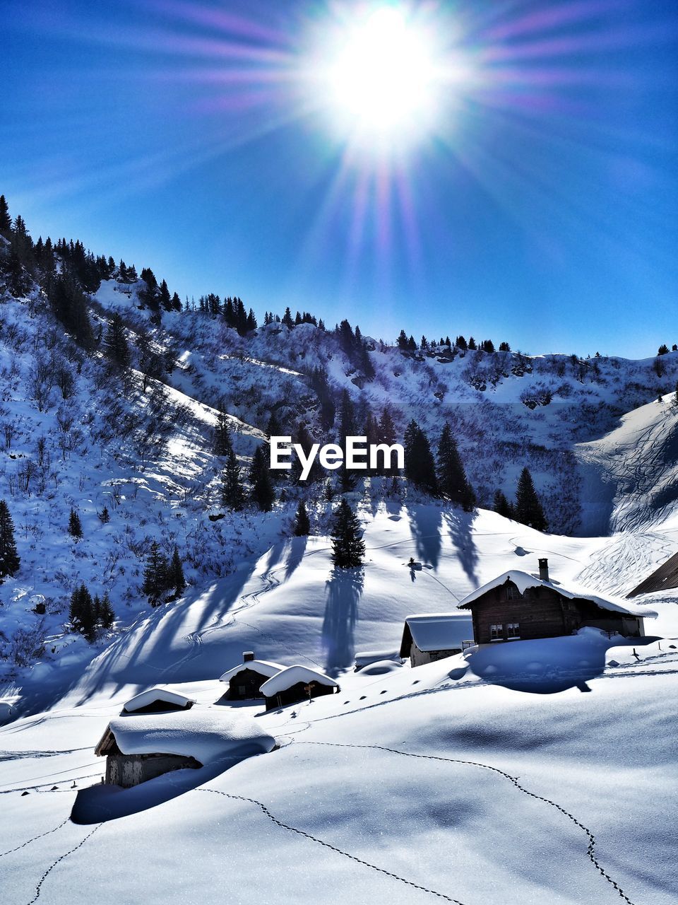 Houses on snow covered mountain on sunny day