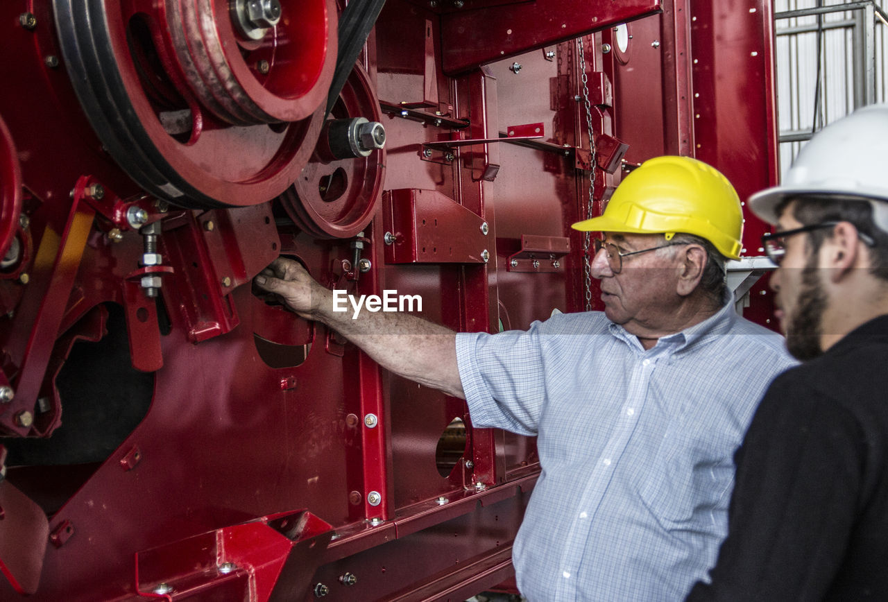 Men discussing while standing by machinery