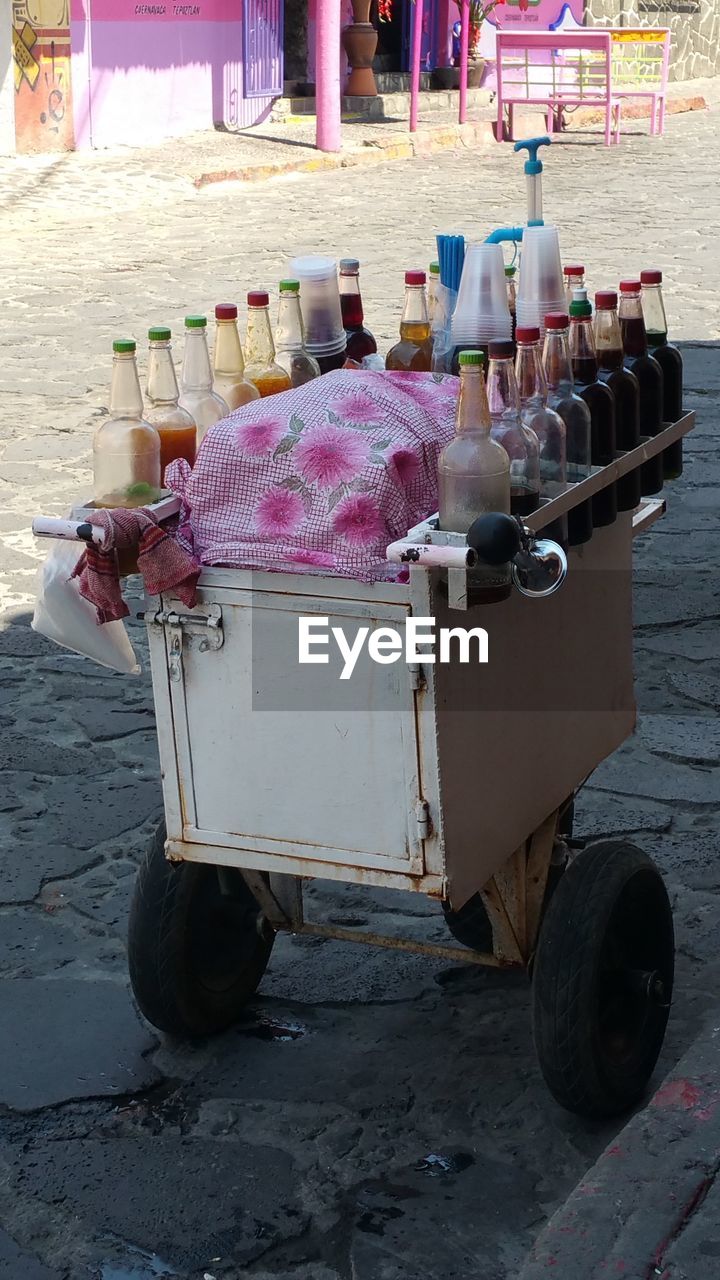 Shaved ice syrup bottles on push cart for sale