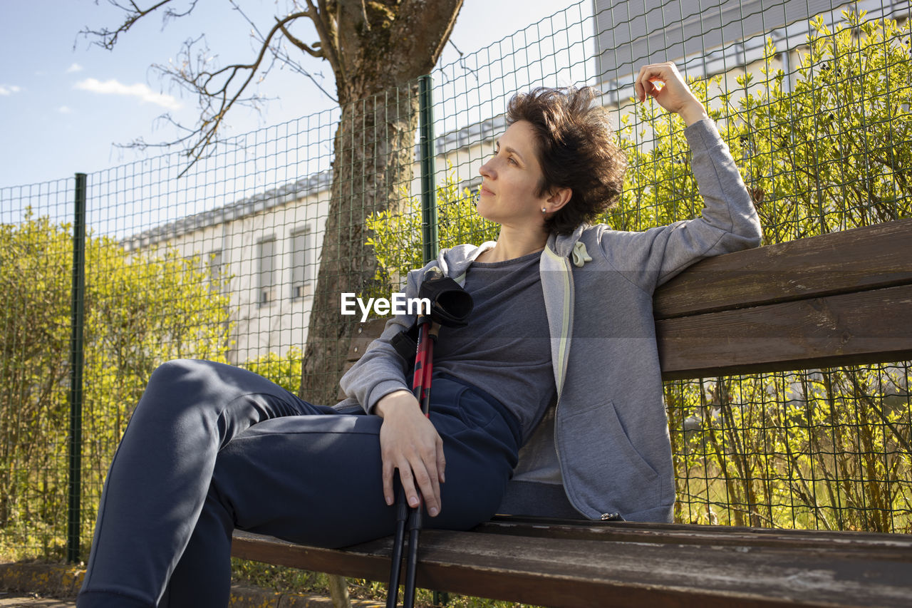 Pretty woman sits on bench holding sticks after nordic walking. beautiful happy caucasian woman