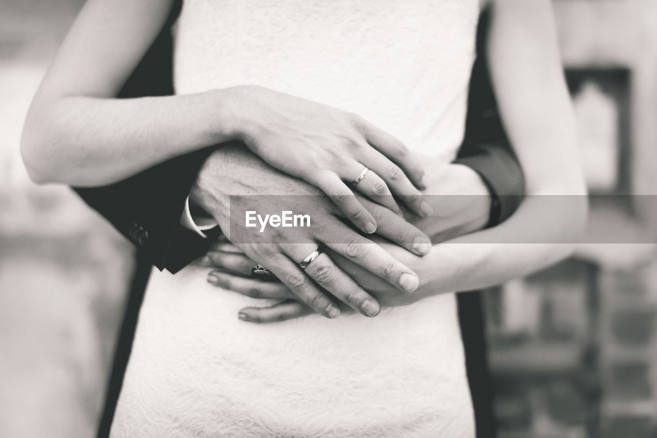 Cropped hands of bridegroom embracing bride during wedding ceremony