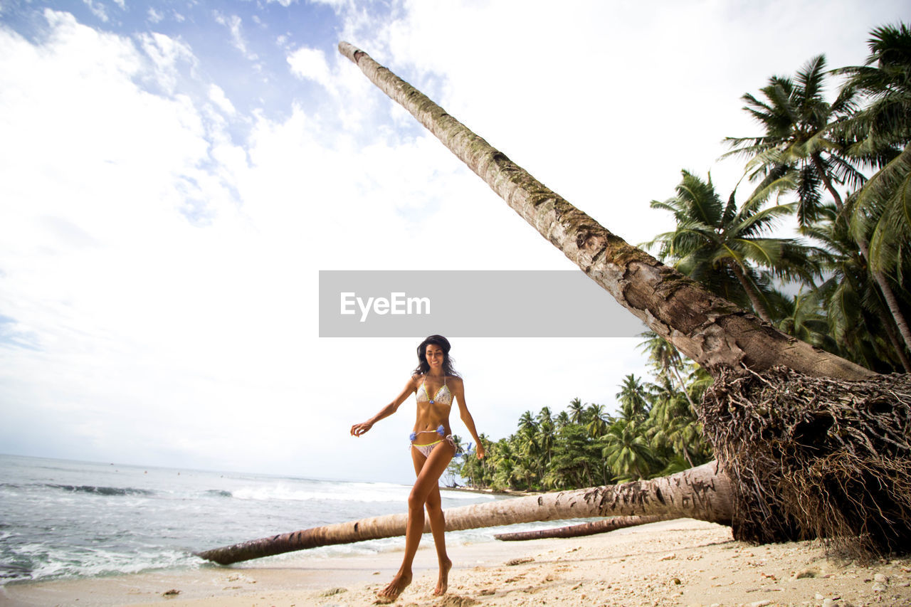 Mid adult bikini woman walking on sandy beach