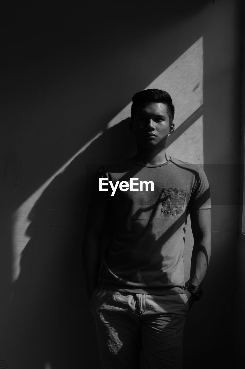 Young man standing against wall