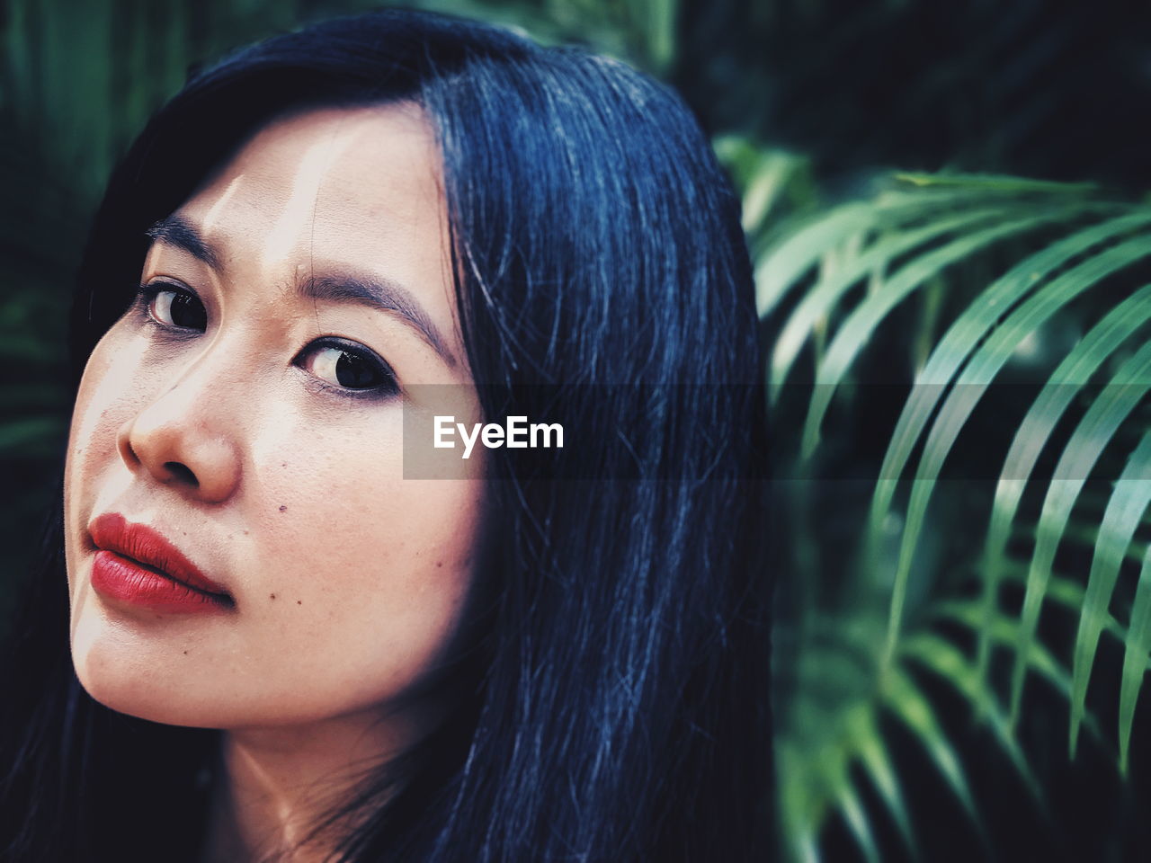 Close-up portrait of young woman by leaves