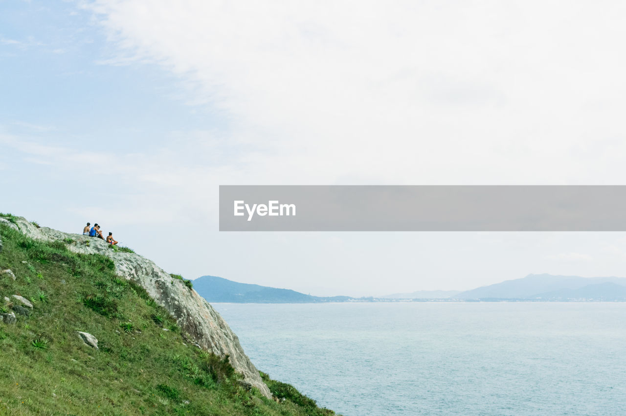 Scenic view of sea by mountain against sky