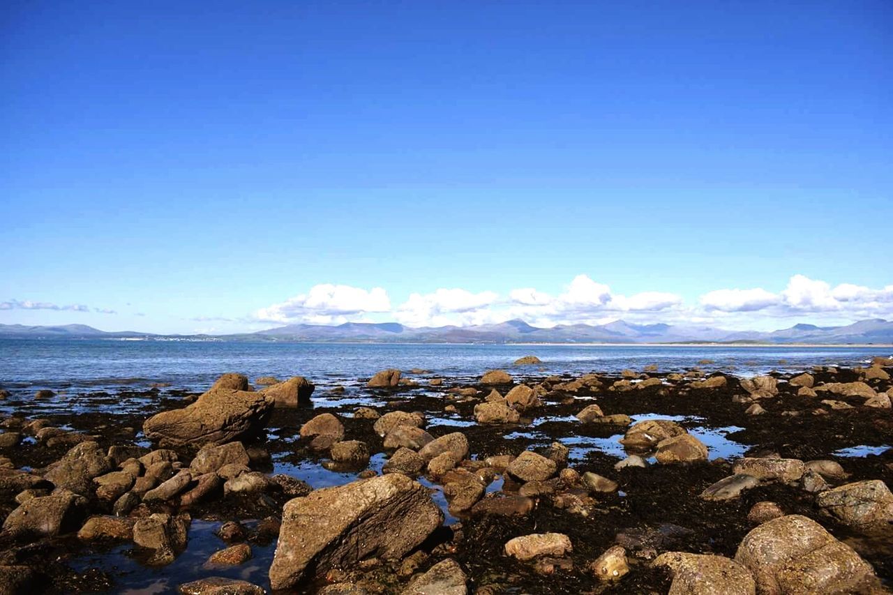 ROCKS ON BEACH AGAINST BLUE SKY