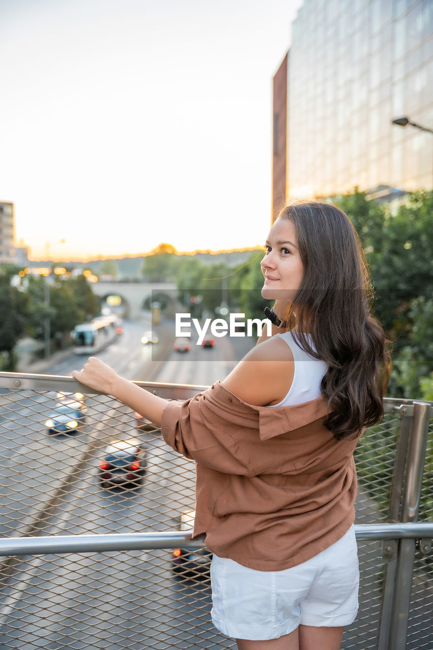 side view of young woman looking away while standing by railing