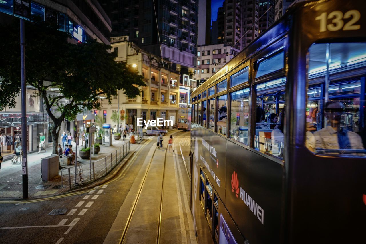 VEHICLES ON ROAD ALONG BUILDINGS AT NIGHT