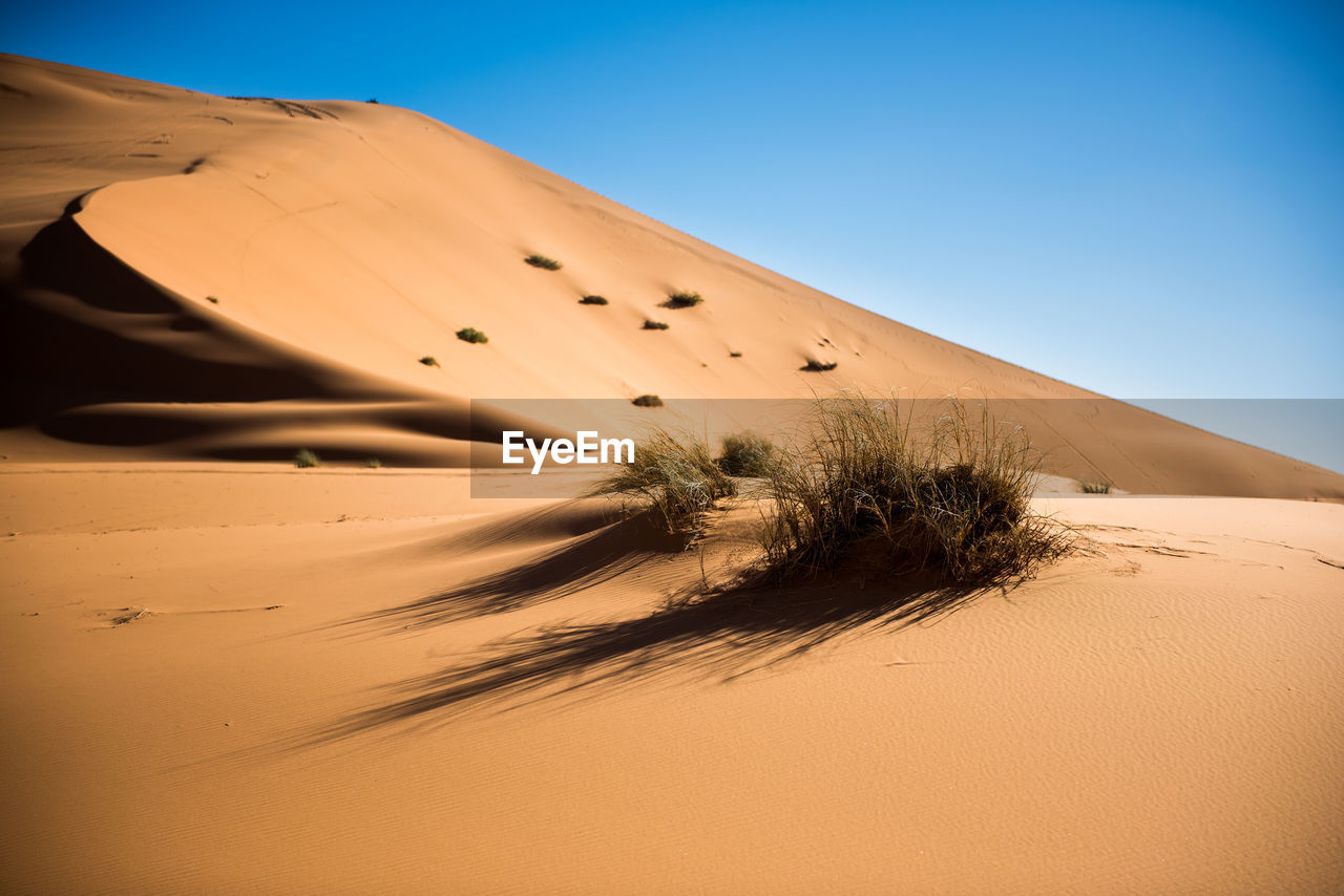 Scenic view of desert against clear blue sky